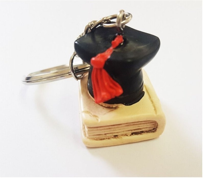 Trade Shop Traesio - Trade Shop - 12 Stück Partygeschenk Schlüsselanhänger Hut Buch Abschluss Glückssymbol Keramik -