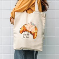 The Alphabet Gift Shop Croissant Bride to Be Tote Bag in Cream